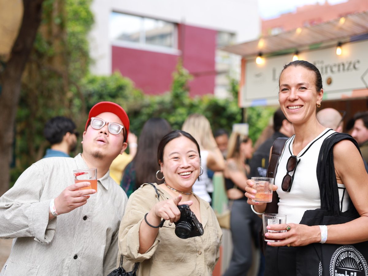 Three guests smiling with cocktails at an outdoor bar gathering