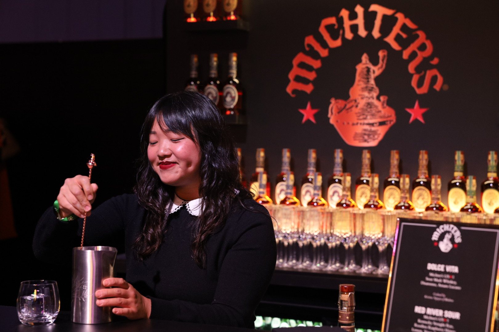 Bartender stirring a cocktail at a whiskey brand bar